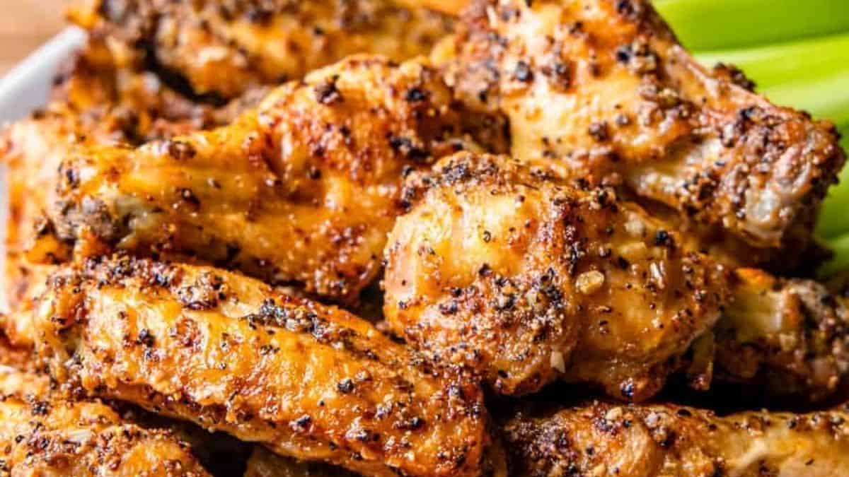 Golden wings with visible black pepper on a serving tray.