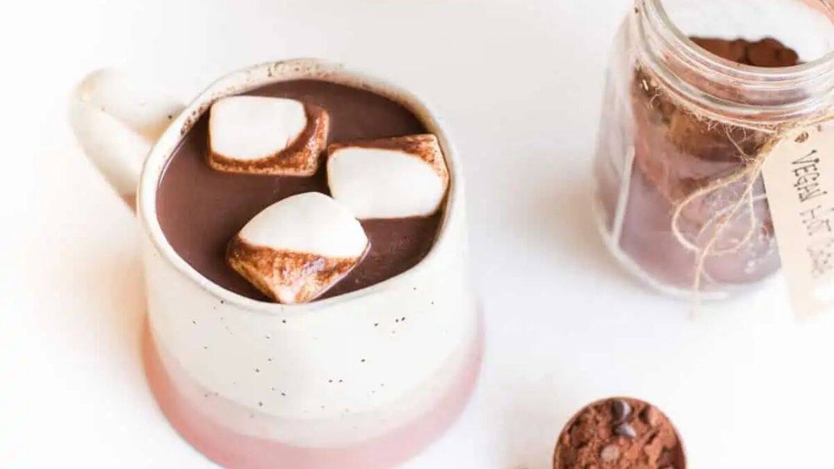 Rich dark hot chocolate in a mug, topped with three large marshmallows.