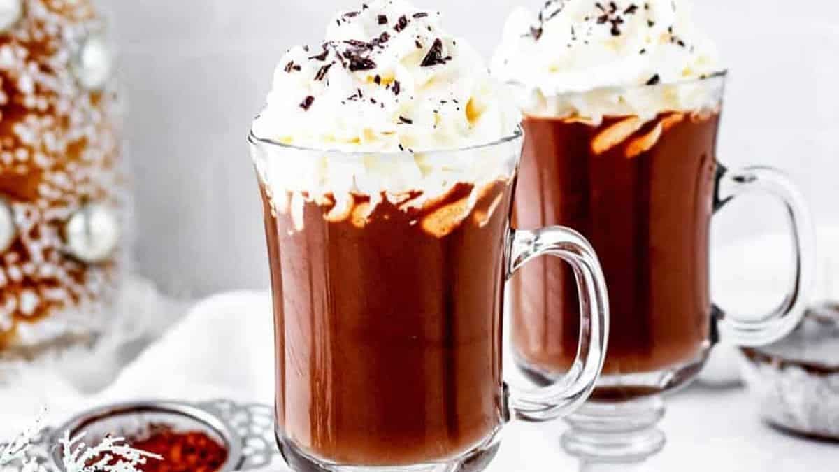 Dark hot chocolate in a clear mug with dark chocolate shavings on top.
