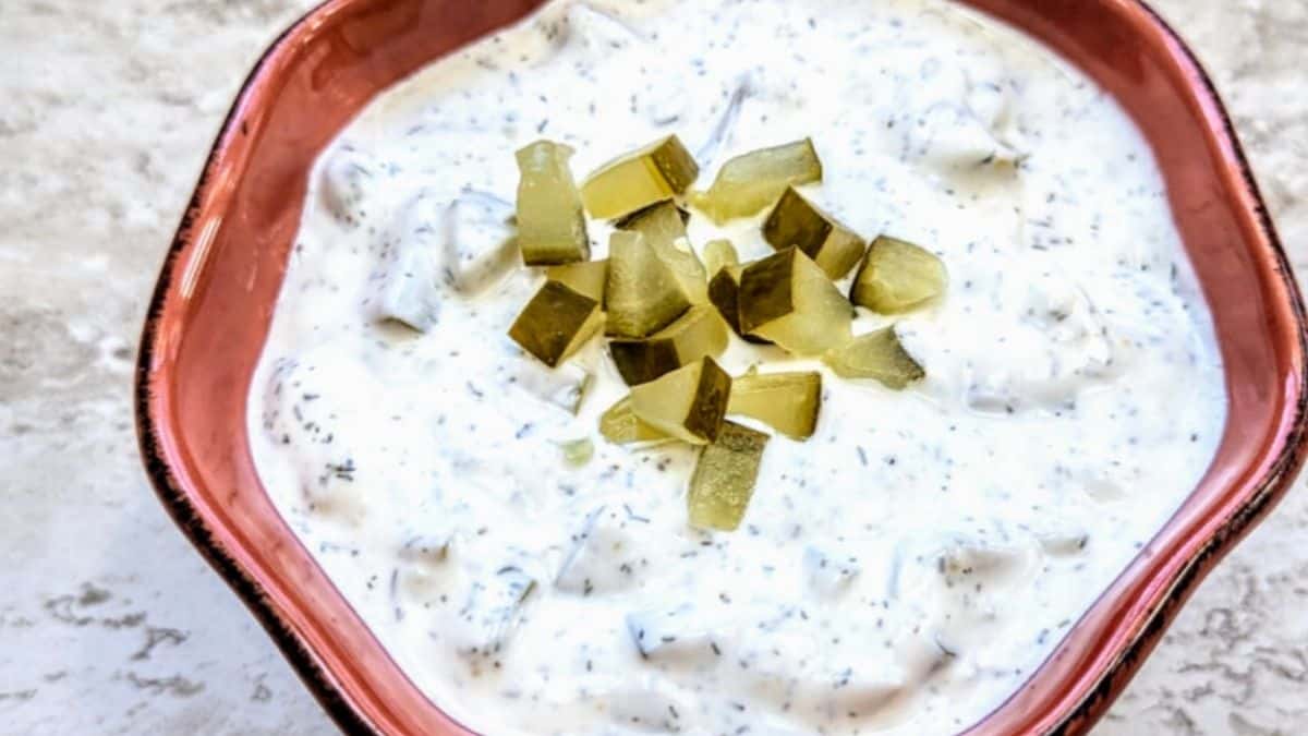 Creamy white dip speckled with chopped dill pickles, garnished with fresh dill and pickle chunks.
