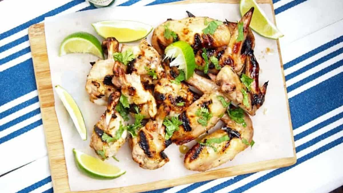 Grilled wings with lime wedges and fresh cilantro garnish.