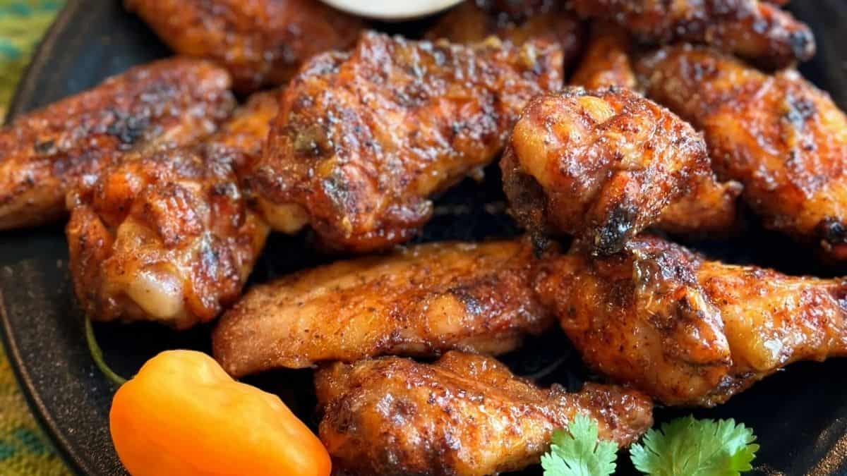 Orange-glazed wings with specks of habanero peppers and fresh mango chunks on the side.