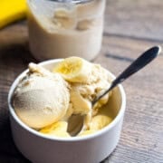 Two scoops of super creamy banana ice cream in a bowl with banana slices.