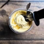An ice cream scoop lifting homemade Ninja Creami vanilla protein ice cream, showing its rich and creamy consistency.
