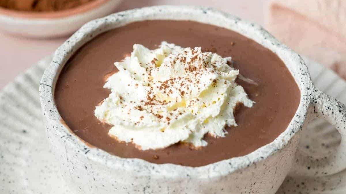 Rich hot chocolate topped with whipped cream and a dusting of cocoa .