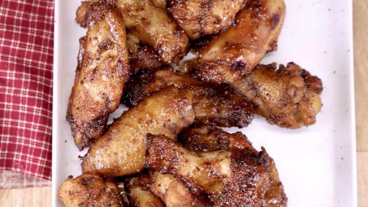 Dark mahogany colored wings with a sticky maple glaze on a serving tray.