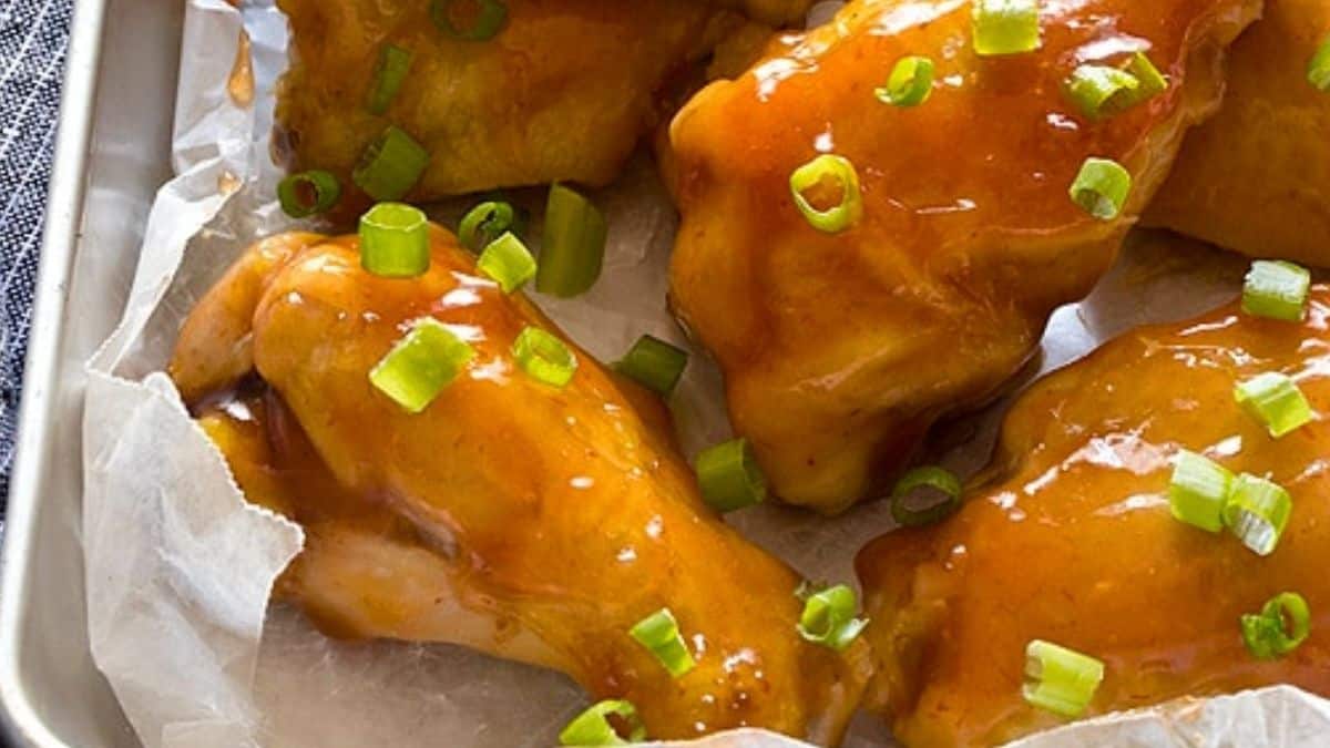 Glossy chicken wings garnished with green onions.