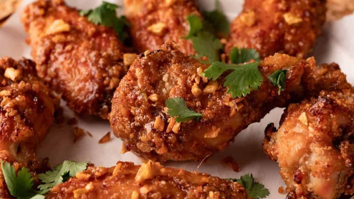Golden crispy wings on a tray with fresh herbs.
