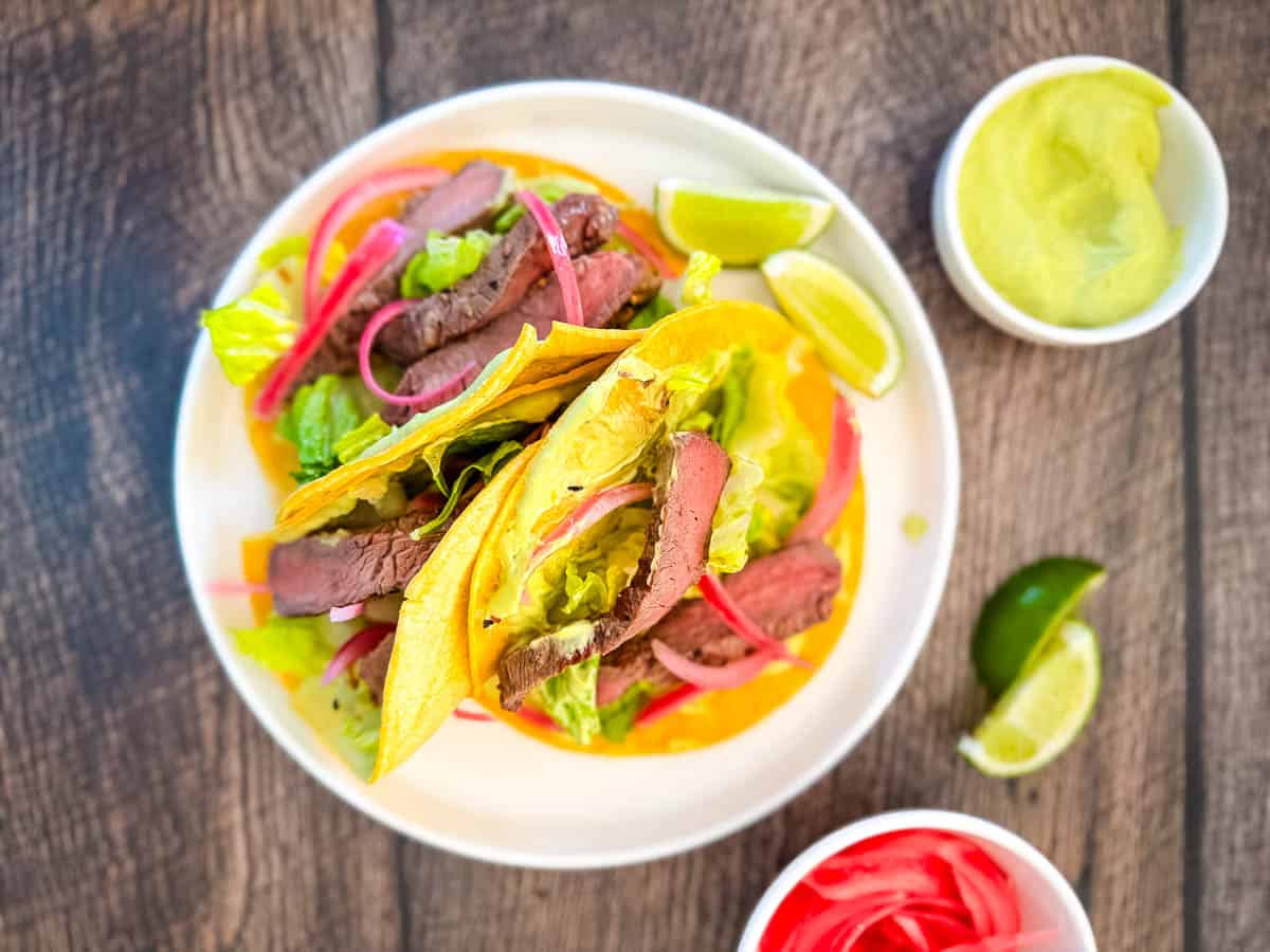 Pickled red onions on a street taco with avocado slices.