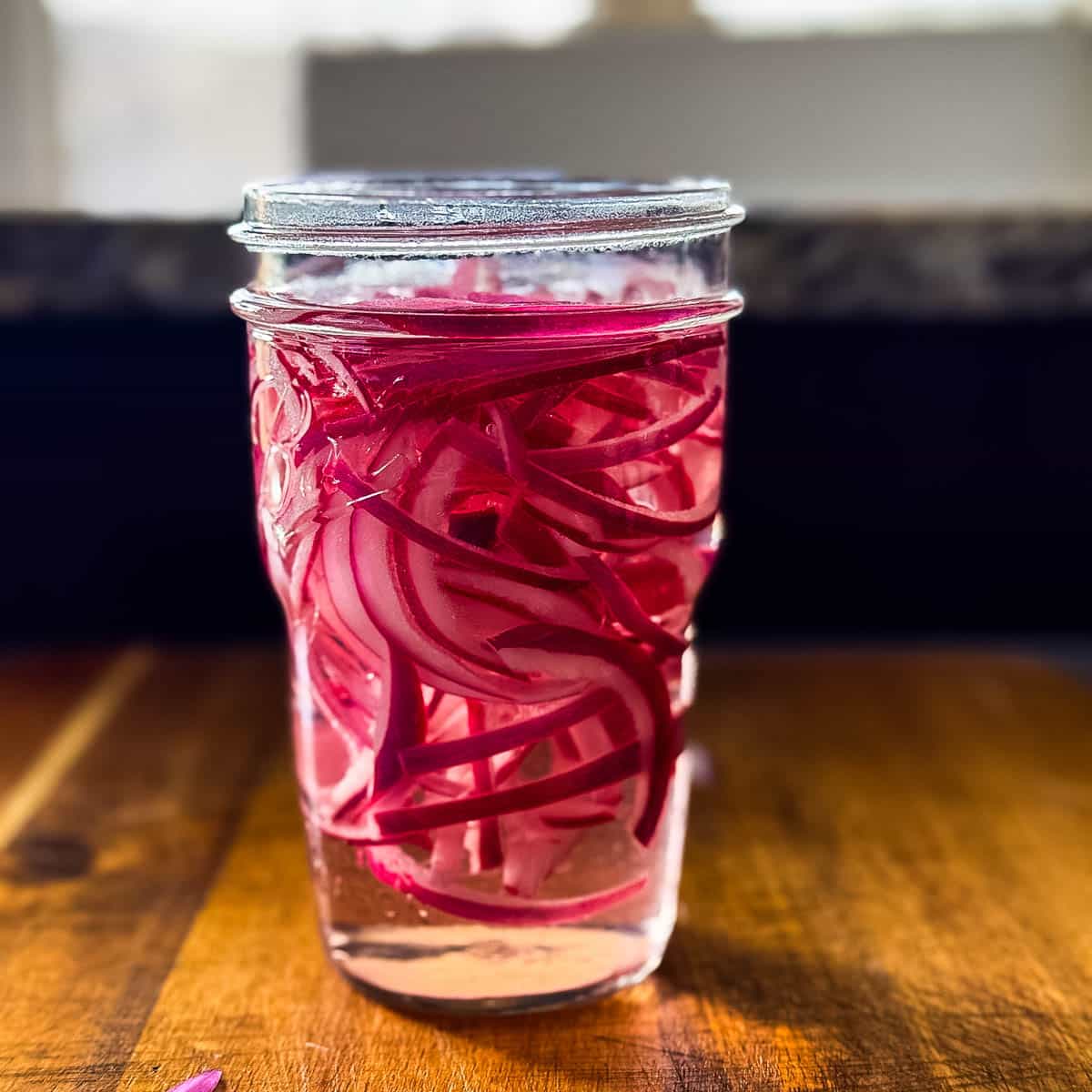 Process photo of quick pickled onions in a jar.