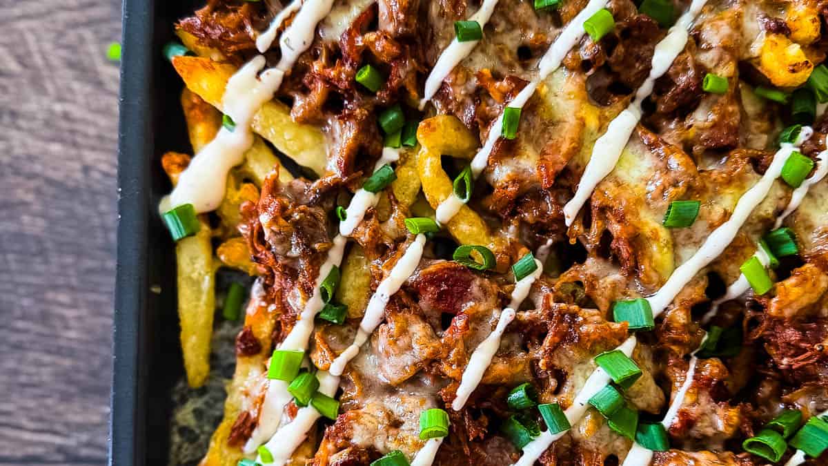 Loaded BBQ pulled pork fries on a sheet pan, ready to serve.