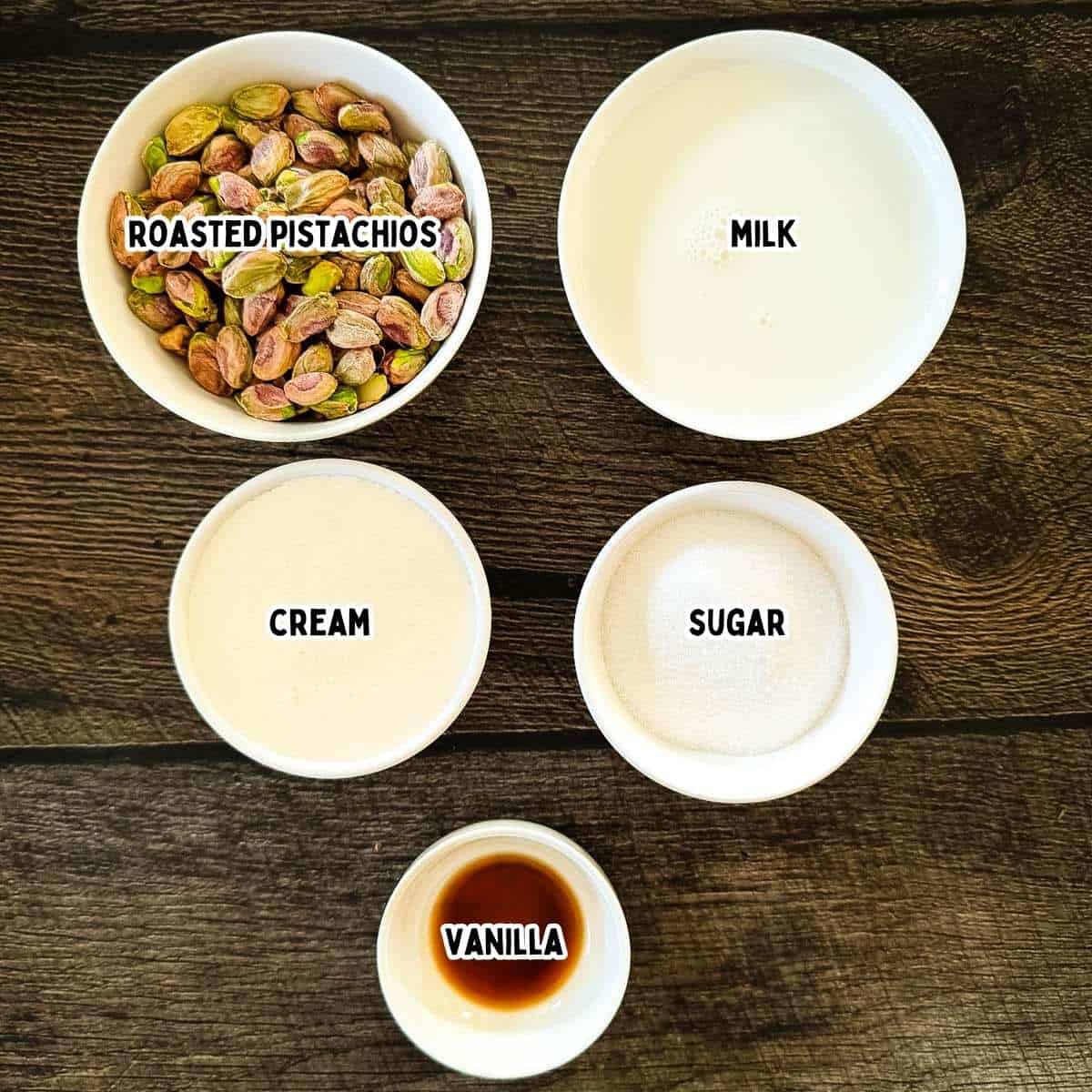 Labeled ingredients laid out on a countertop: pistachios, milk, cream, sugar, and vanilla.