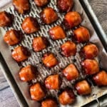 Bacon-wrapped smoked meatballs glazed and served on a grilling tray.
