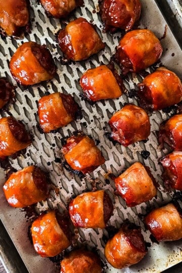 Bacon-wrapped smoked meatballs glazed and served on a grilling tray.