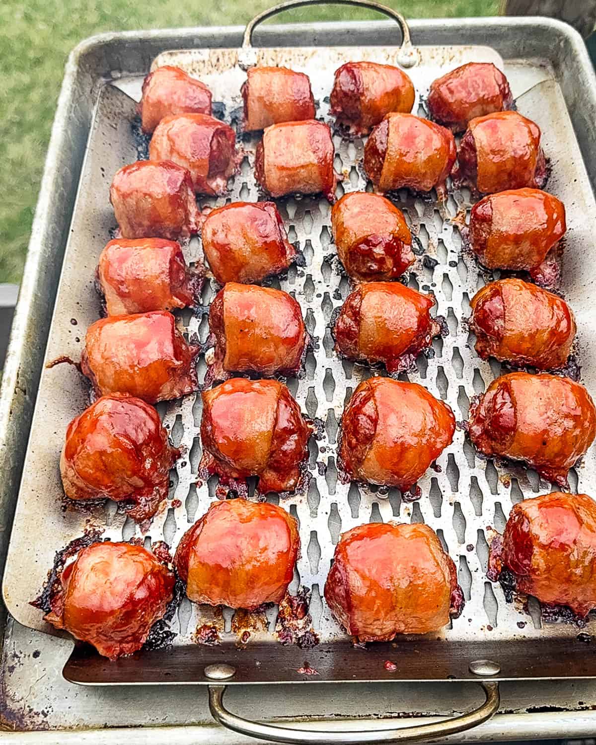 The finished meatballs on the grilling tray beside the pellet grill.