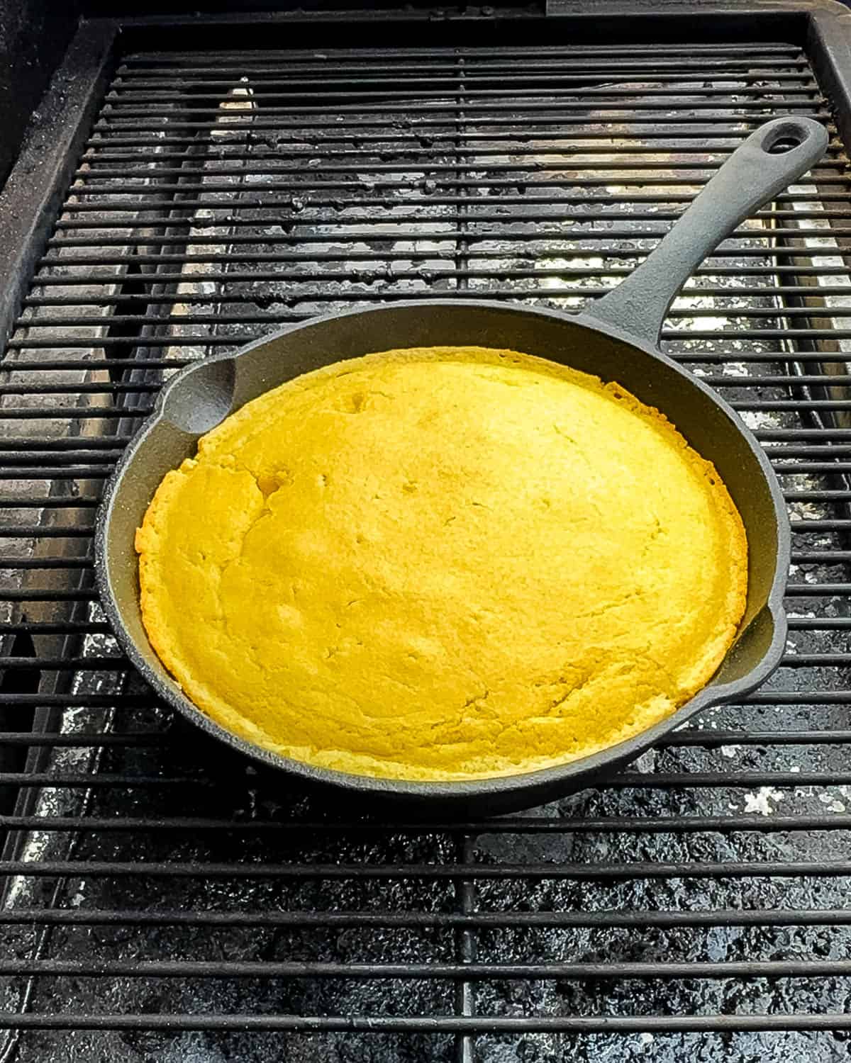 Golden brown cornbread smoking on pellet grill at 350°F.