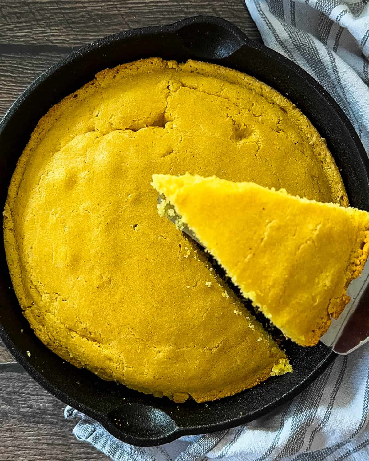 Slicing smoked cornbread with crispy edges and soft center.