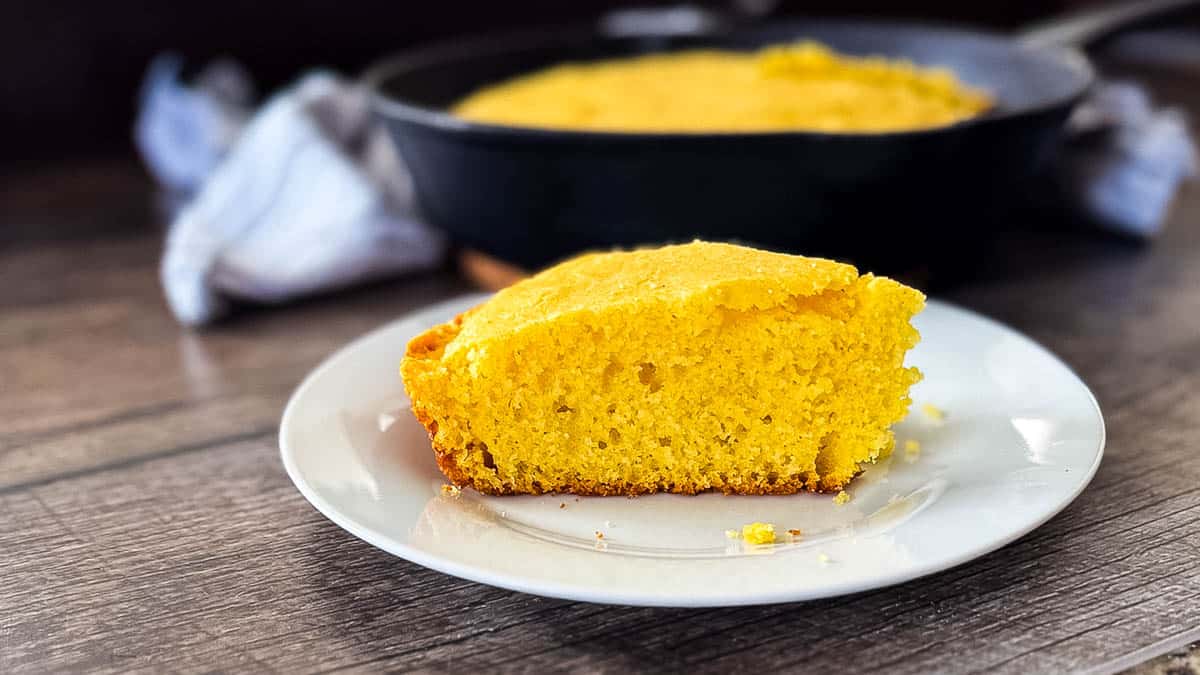 A slice of moist cornbread on a white plate.