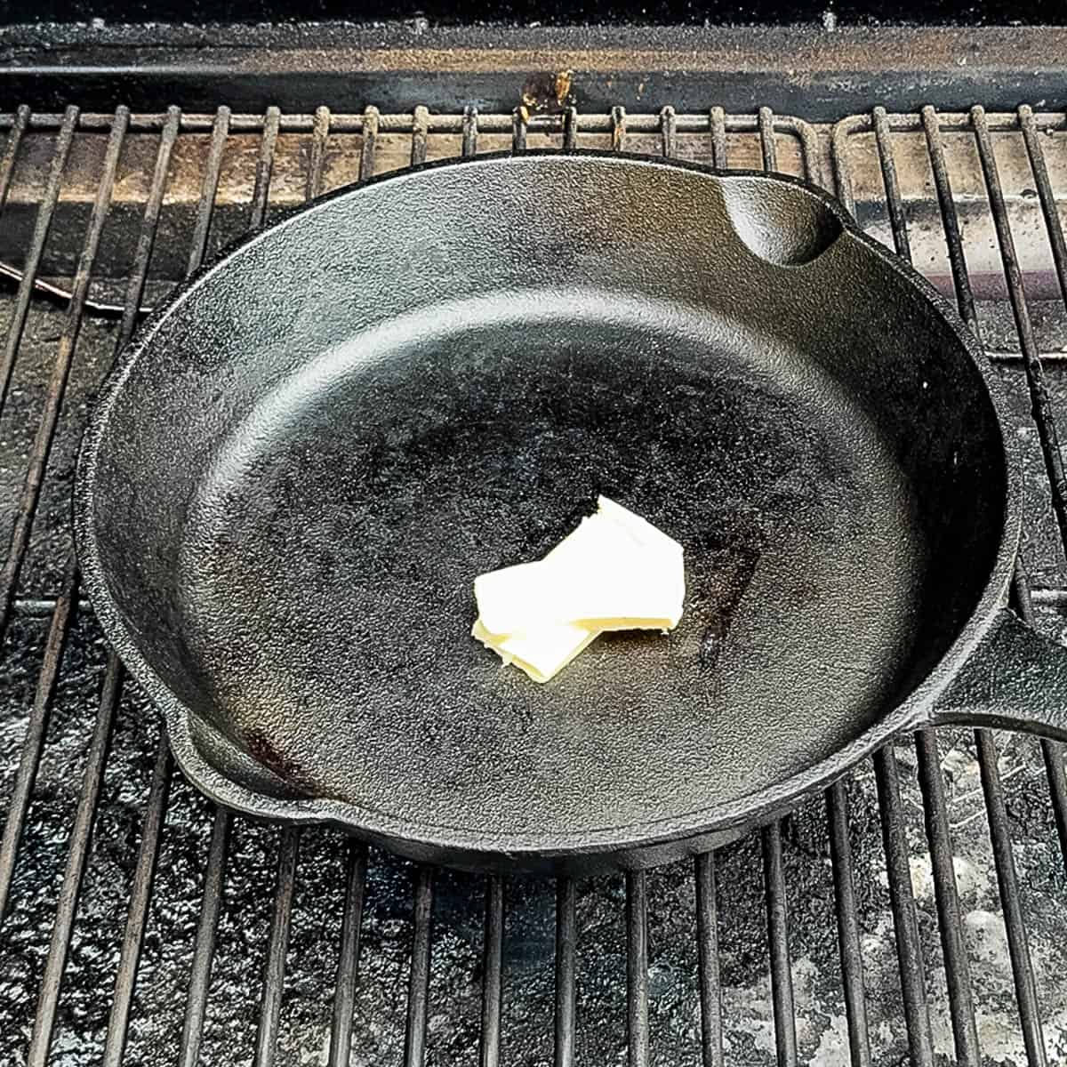Melting butter in hot cast iron skillet on smoker grates.