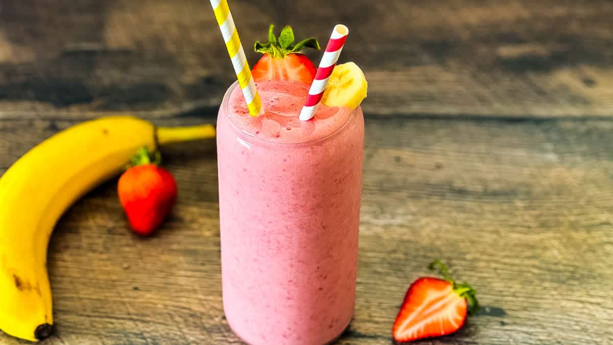 Strawberry banana smoothie in a glass with a fresh strawberry.