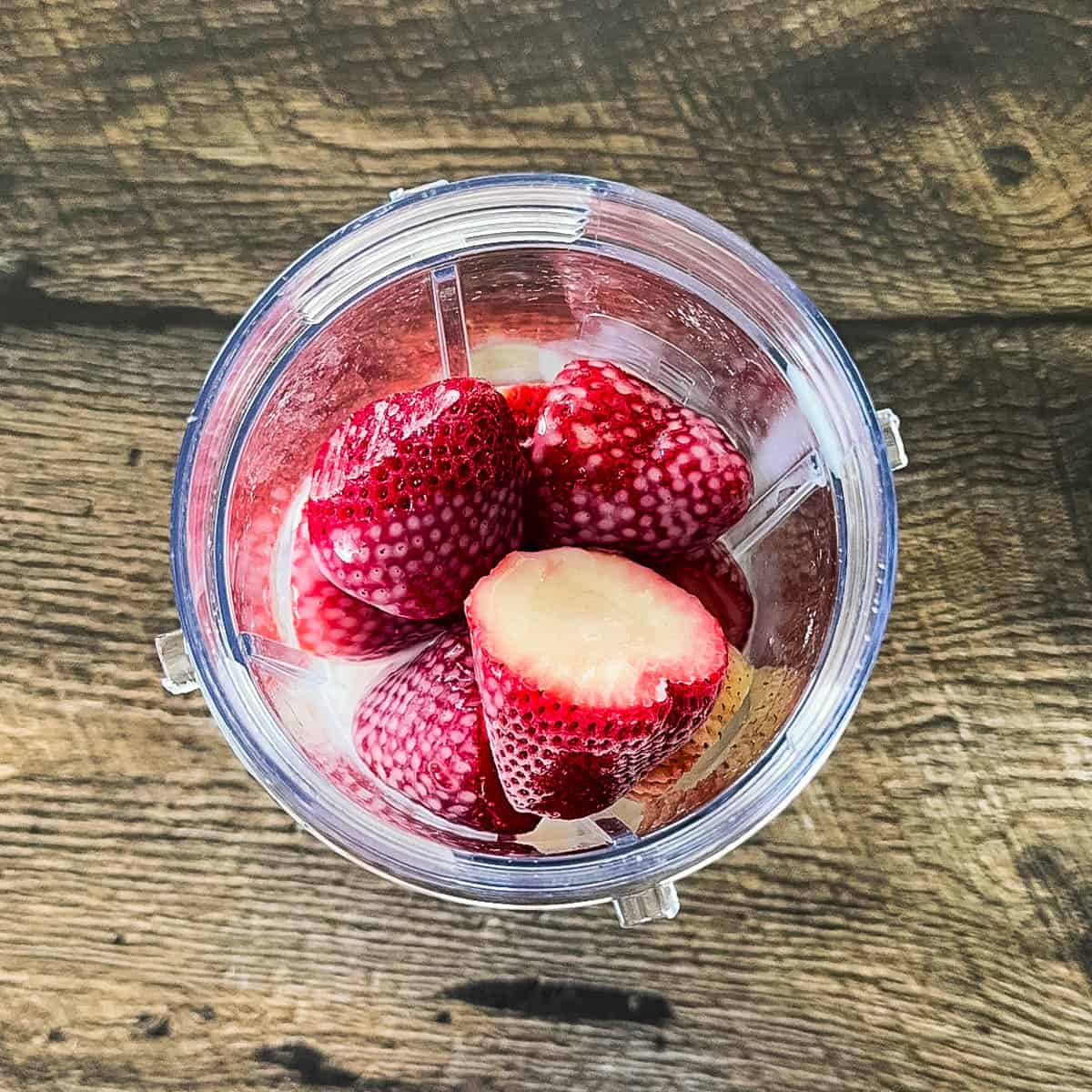 Banana, frozen strawberries, almond milk, and vanilla in a blender.