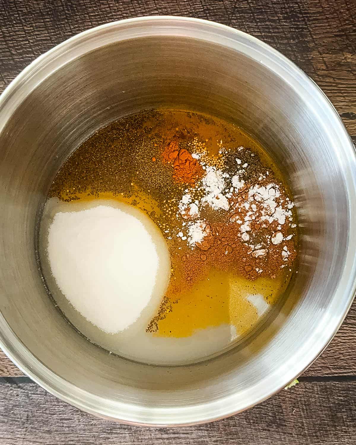 Vinegar, sugar, and spices added to a stainless steel pot on the stove for zucchini relish brine.