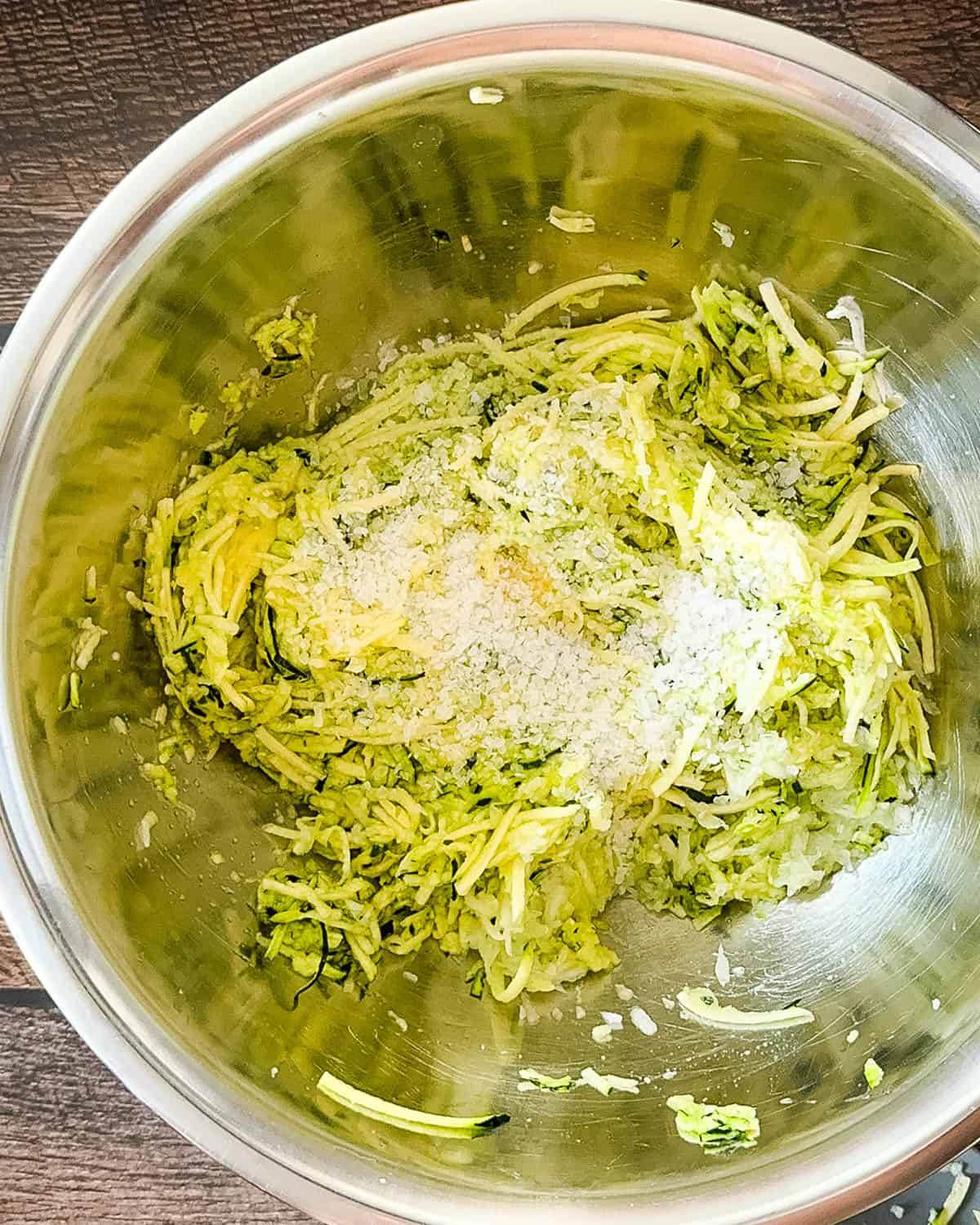 Chopped zucchini and onion mixed with pickling salt in a large mixing bowl.