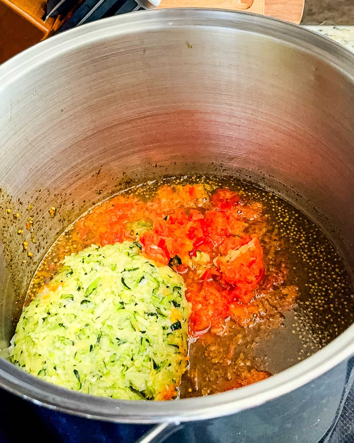 Diced red and green bell peppers added to the simmering relish mixture in a large pot.