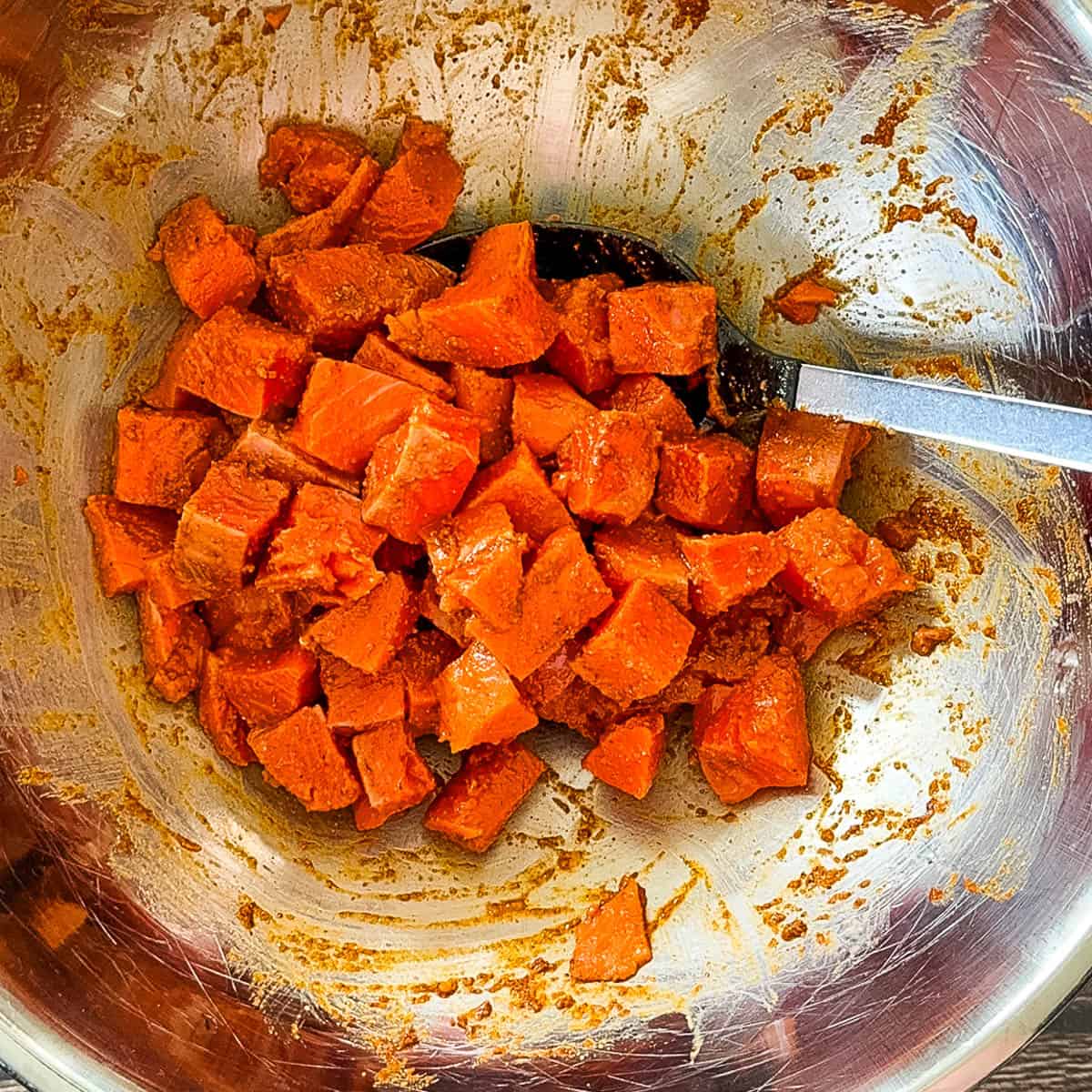 Cubed salmon tossed with spices and lime juice in a bowl.