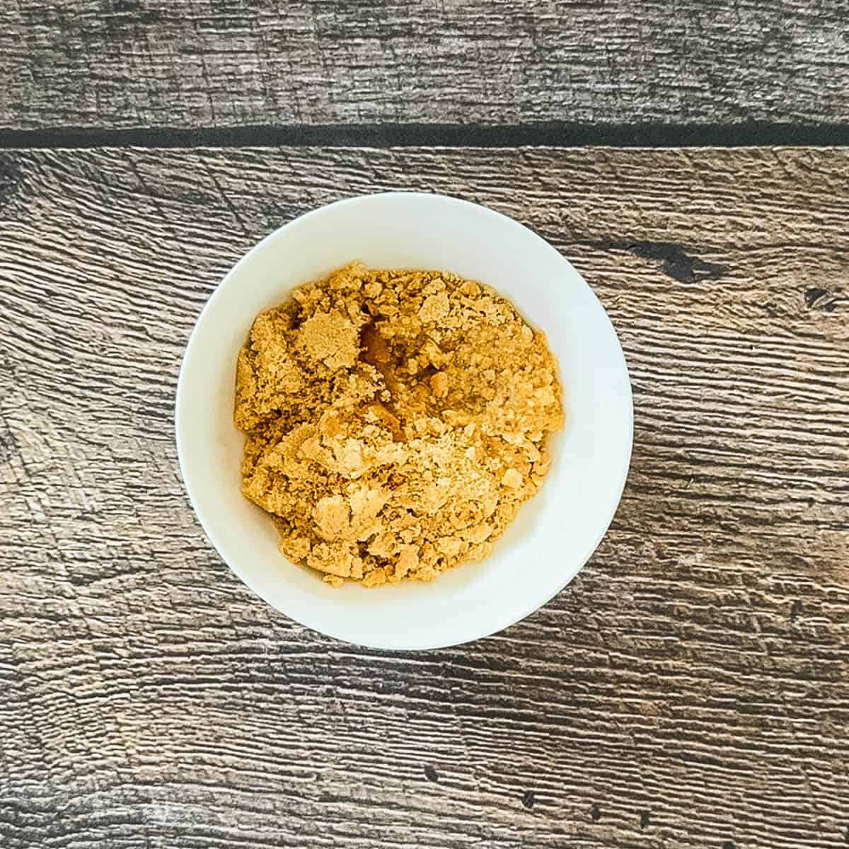 Graham cracker crumbs in a small bowl with brown sugar and melted butter.