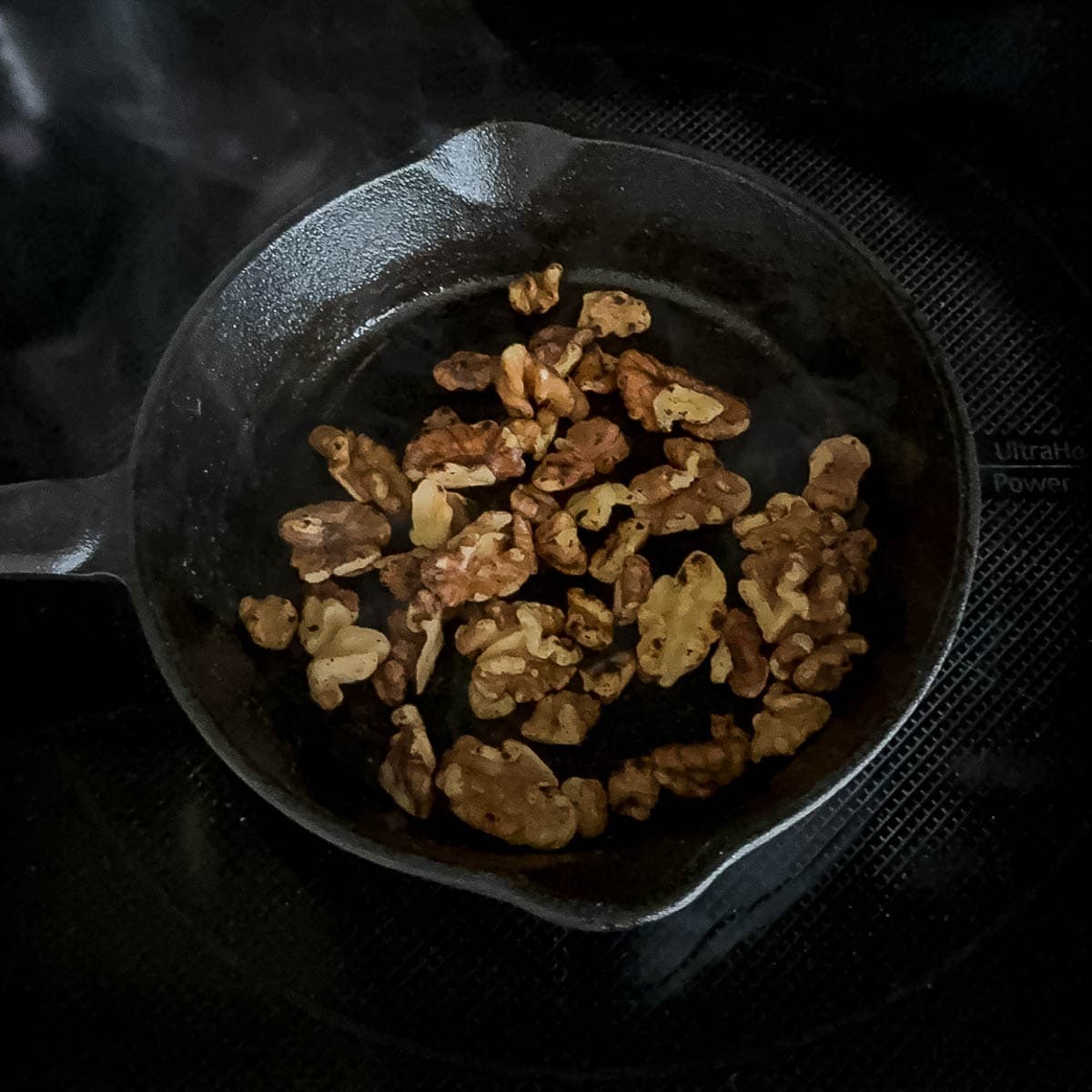 Toasted walnuts in a small cast iron skillet.