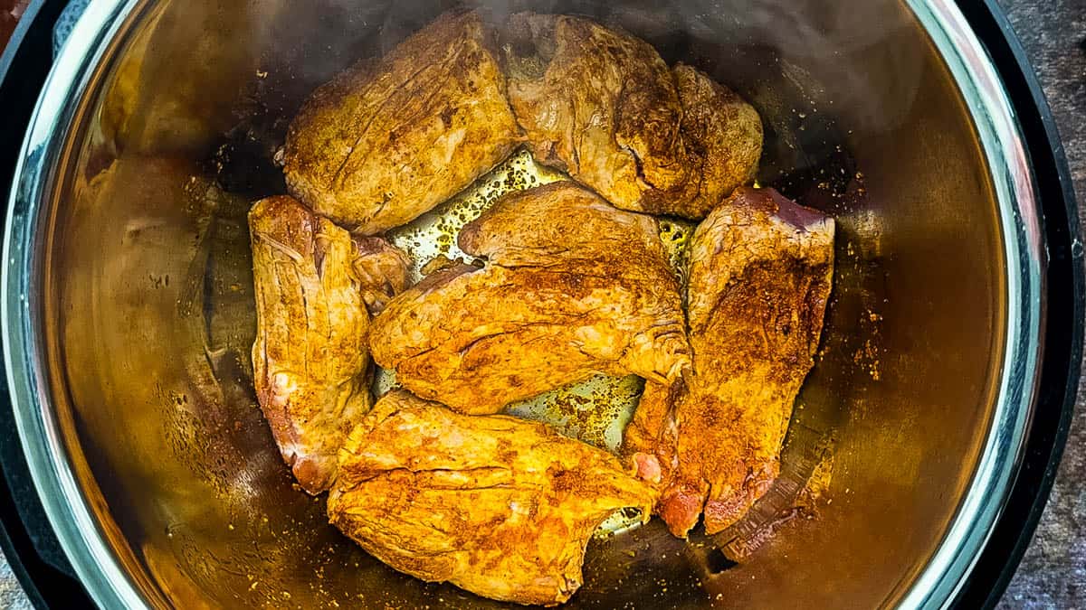 Golden brown pork tenderloin pieces searing inside the Instant Pot.
