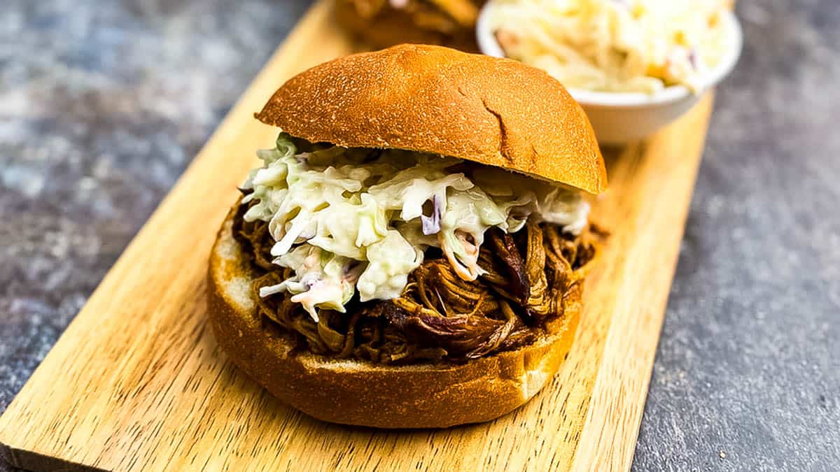Pulled pork sandwich in a bun, topped with creamy coleslaw.
