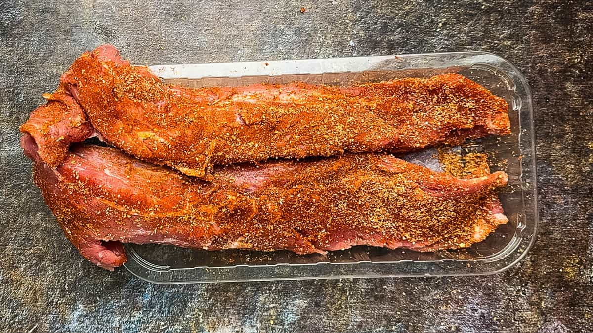 Pork tenderloin coated with spice rub before cooking.