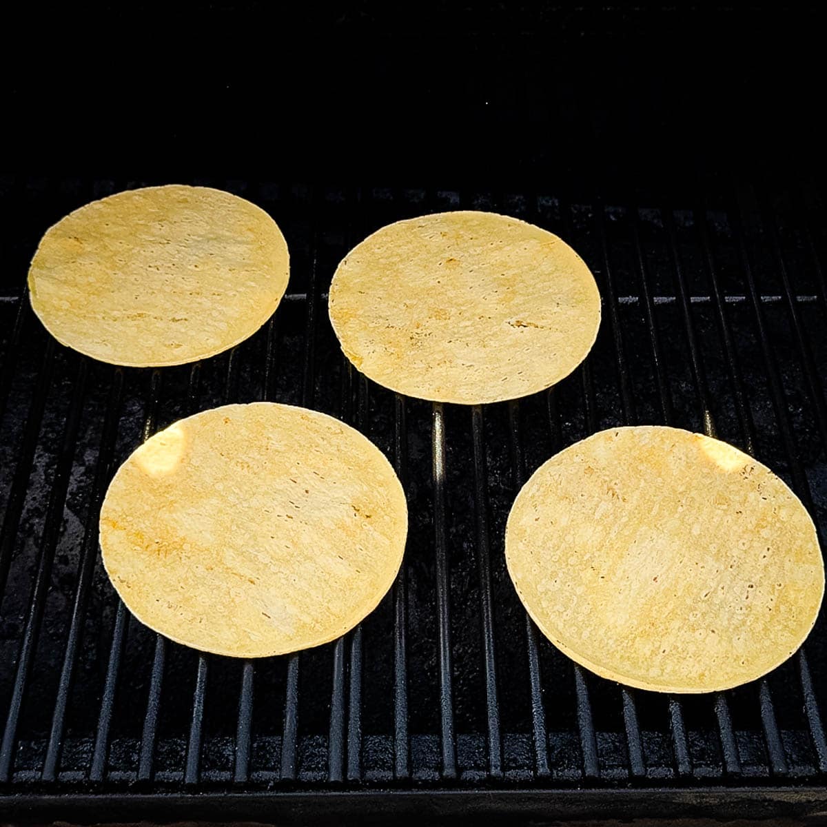 Warming tortilla shells on the grill grates of a pellet smoker.