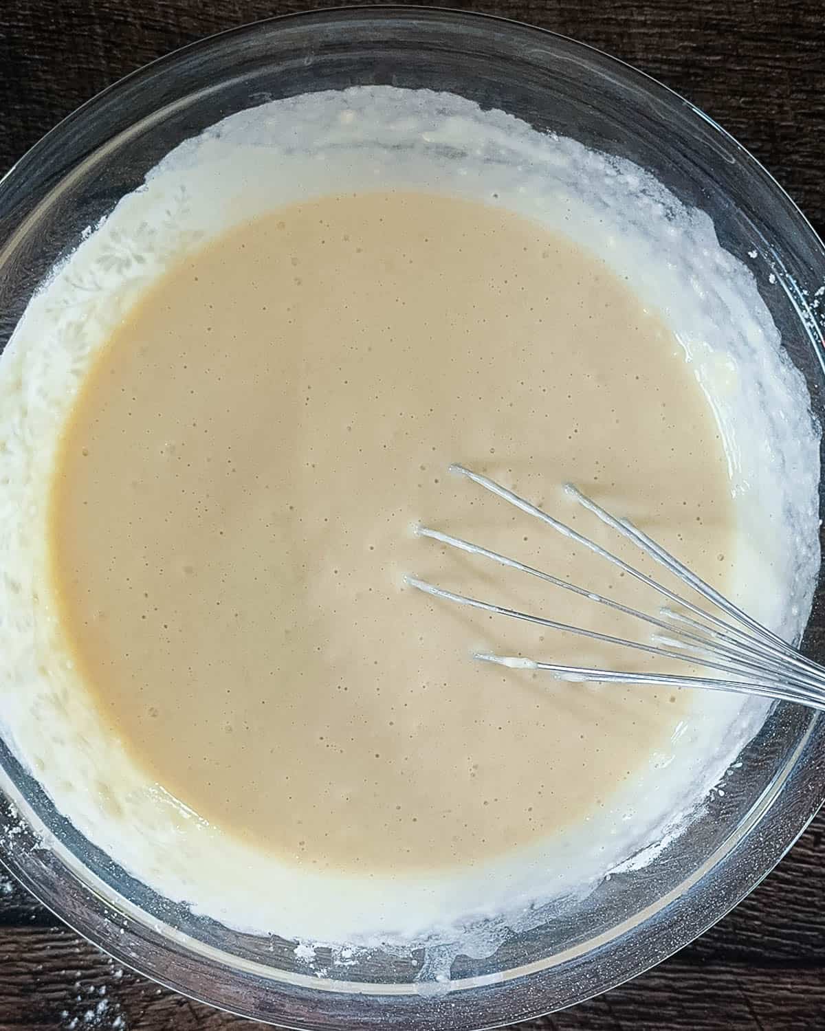Prepared waffle batter resting in a glass mixing bowl.