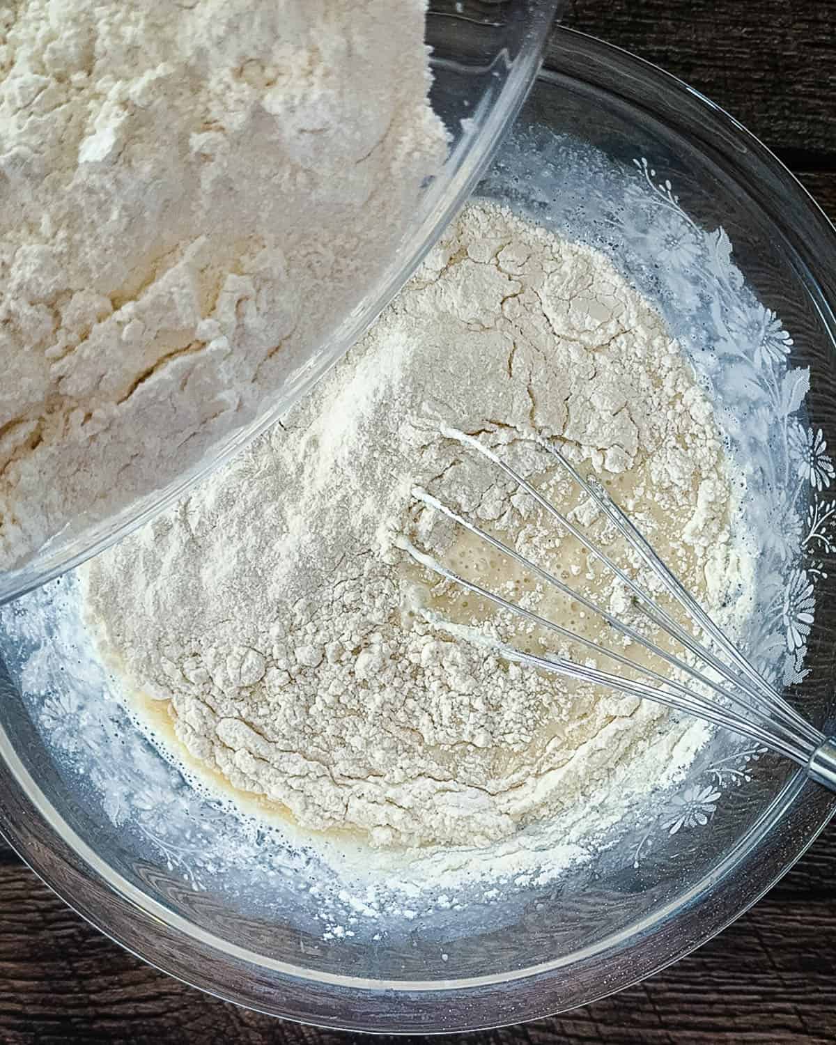 Dry flour mixture being poured into wet ingredients to make sourdough discard waffle batter.