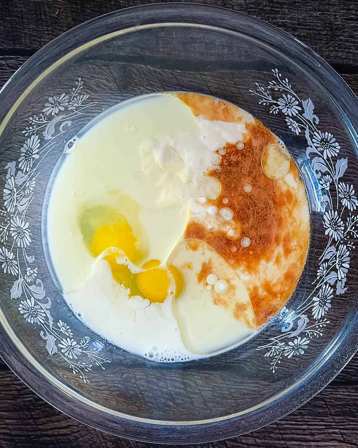 Smooth sourdough discard waffle batter in a glass mixing bowl with a whisk.