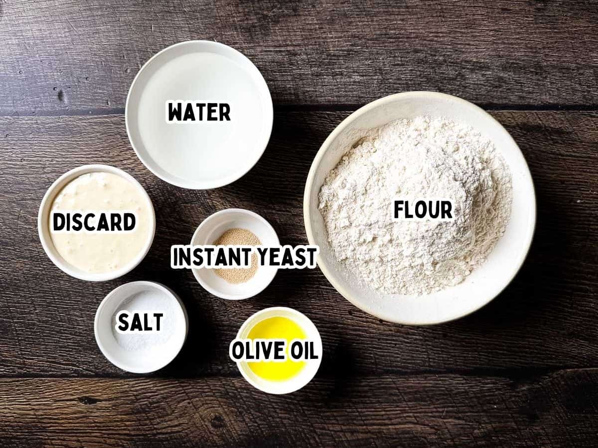 Flour with water, yeast, salt, olive oil, and discard in bowls on dark wooden surface.