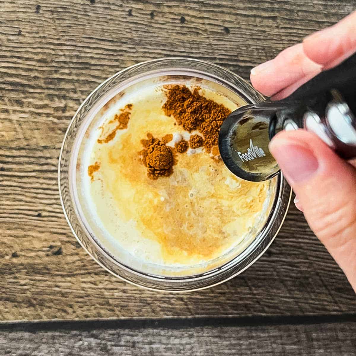 A milk frother blending the ingredients in a pint container.