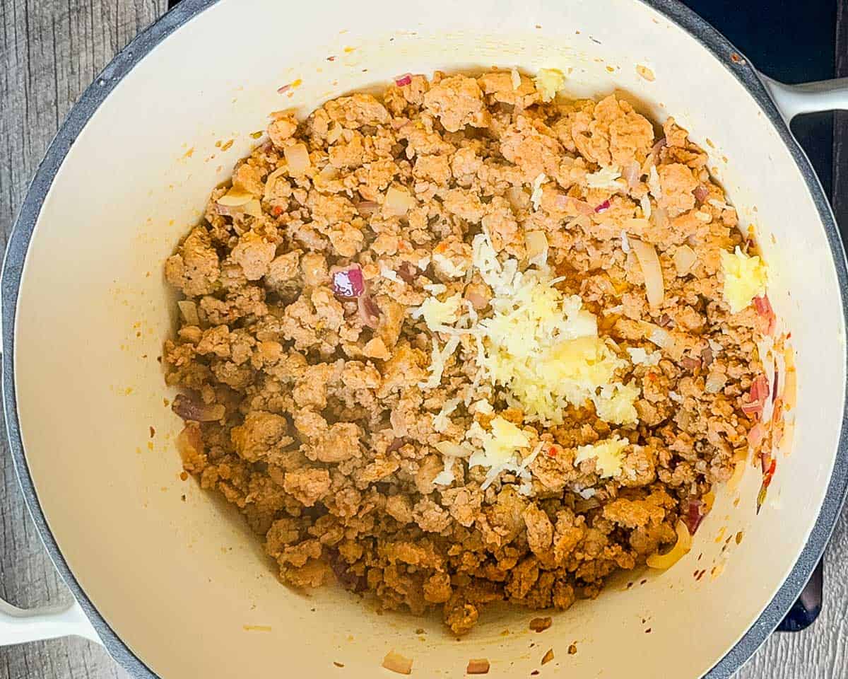 Onions and sausage sautéing together in a large pot.