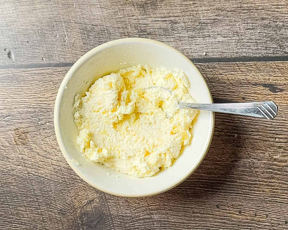 Cheese mixture stirred together in a white bowl.