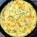 Creamy smoked mashed potatoes in a cast iron skillet topped with paprika and chives, fresh off the Traeger pellet grill.