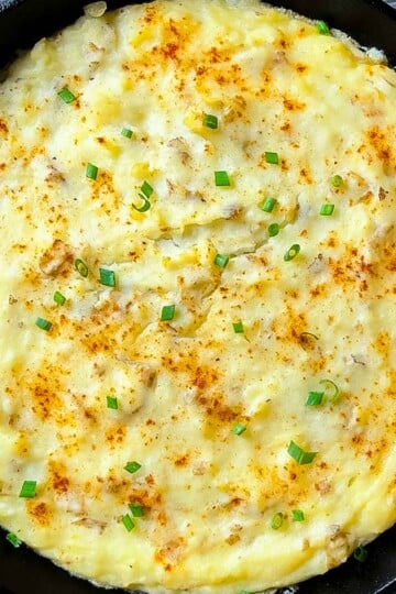 Creamy smoked mashed potatoes in a cast iron skillet topped with paprika and chives, fresh off the Traeger pellet grill.
