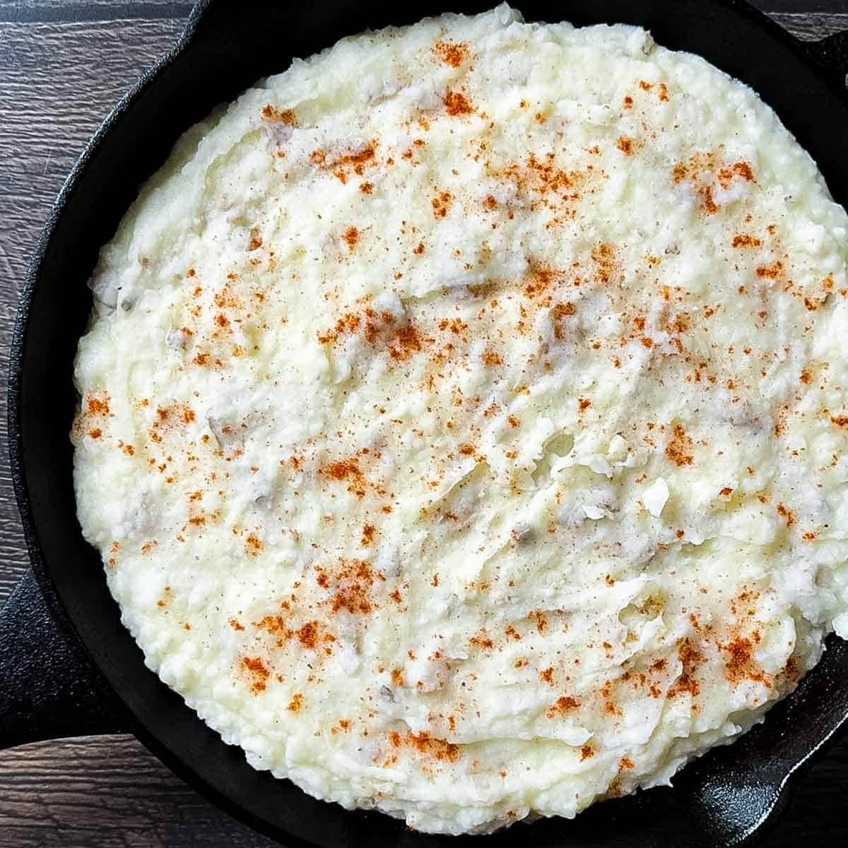 Creamy smoked mashed potatoes in a cast iron skillet topped with smoked paprika.