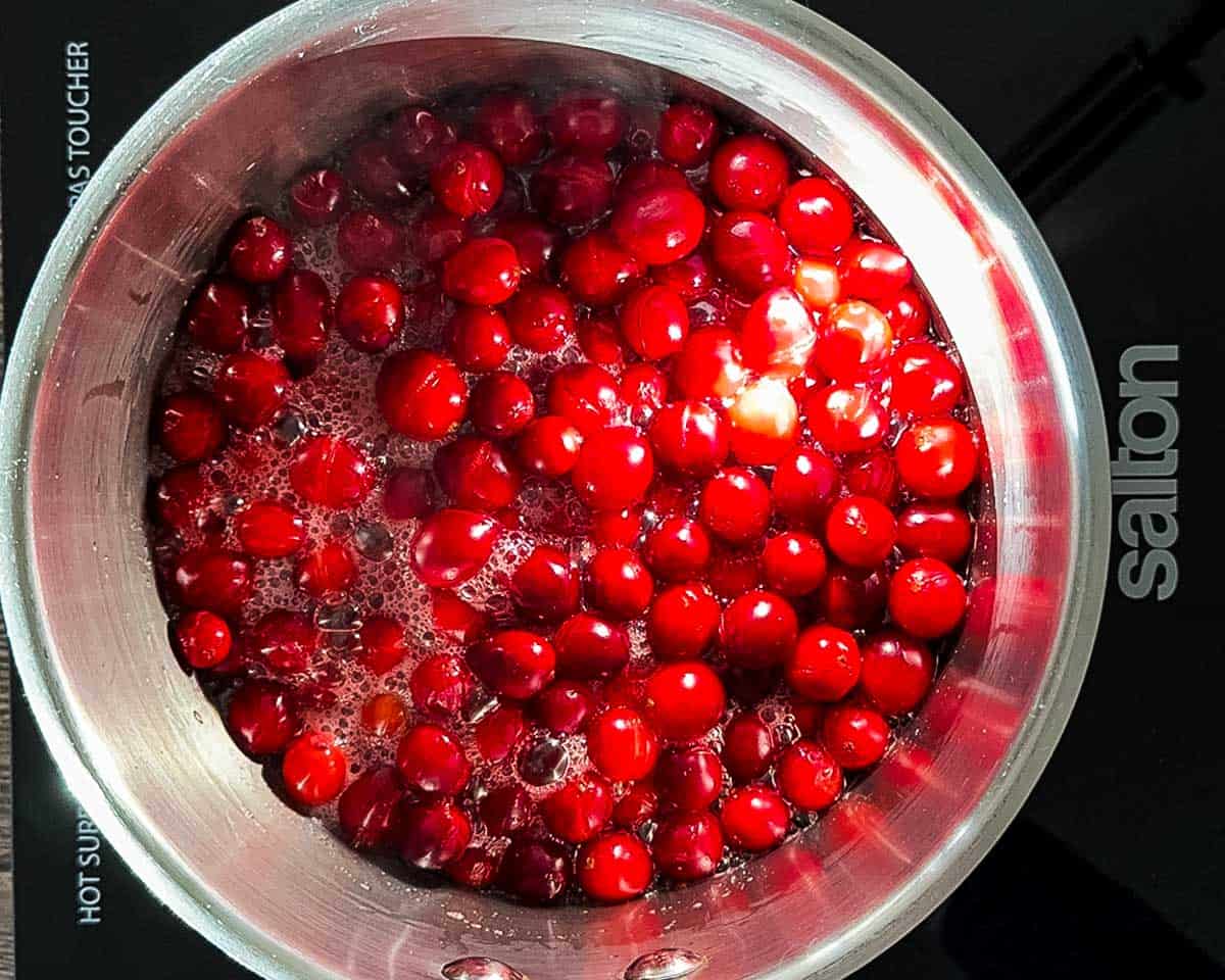 Cranberries boiling on the stove and releasing juices.