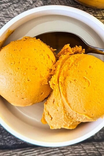 Two scoops of Ninja Creami pumpkin ice cream in a white bowl.