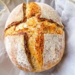 A loaf of homemade whole wheat sourdough bread cooling on a wire rack.
