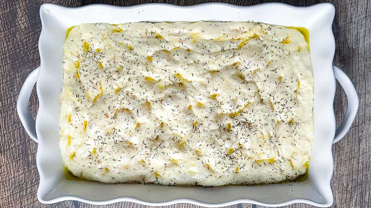 The focaccia sprinkled with herbs before baking.
