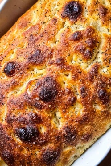 Golden brown sourdough focaccia in a baking dish, ready to be served.